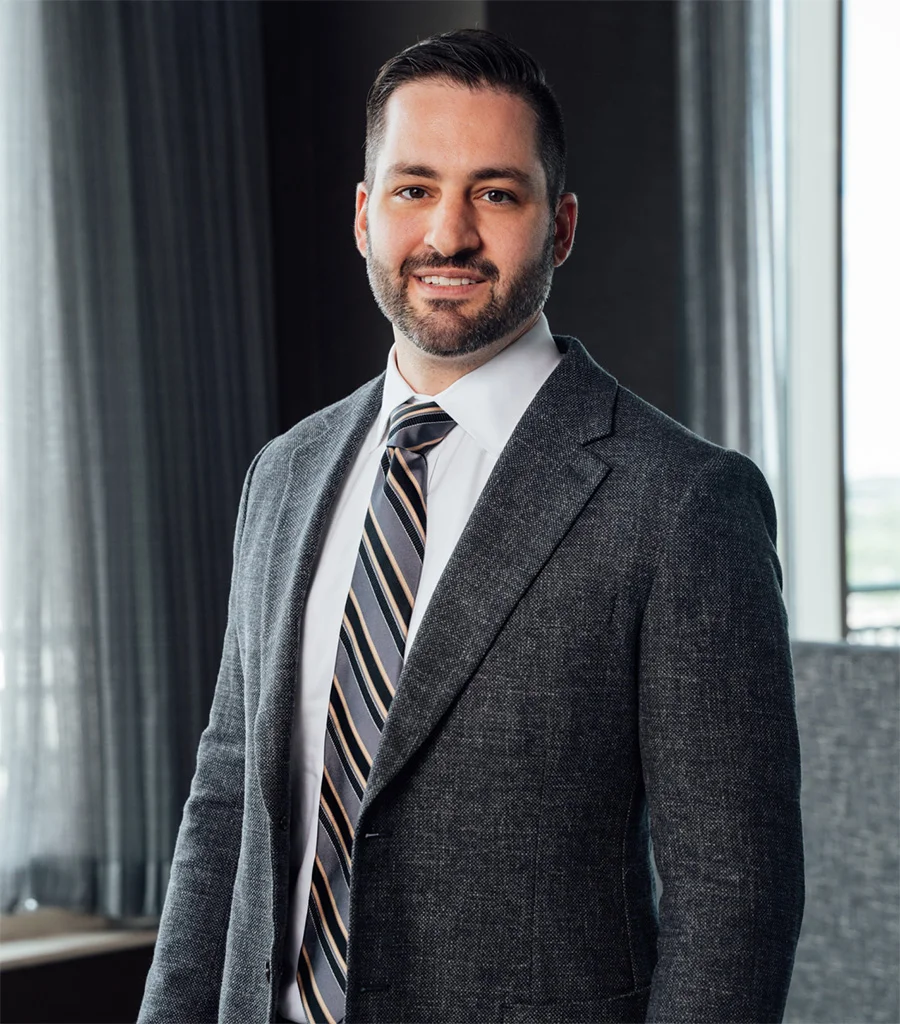 Dr James Economides in dark suit and striped tie standing confidently in modern medical office - Doctor in Chevy Chase, MD
