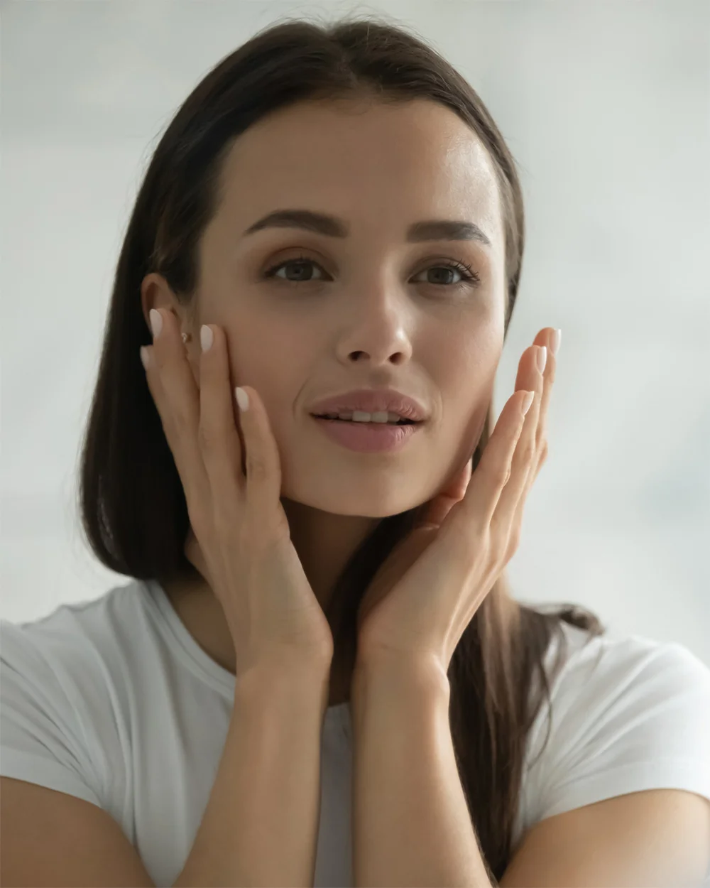 Woman gently touching her face with both hands demonstrating skincare routine and natural beauty - face in Chevy Chase, MD