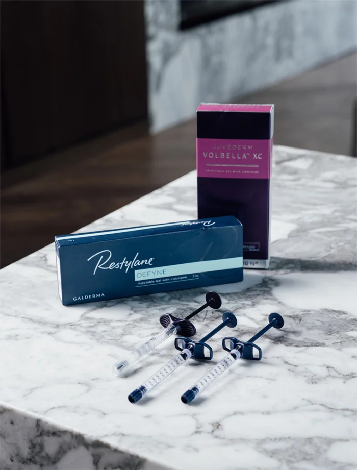 Restylane dermal filler products and syringes displayed on marble surface for cosmetic injectable treatments - Dermal fillers in Chevy Chase, MD