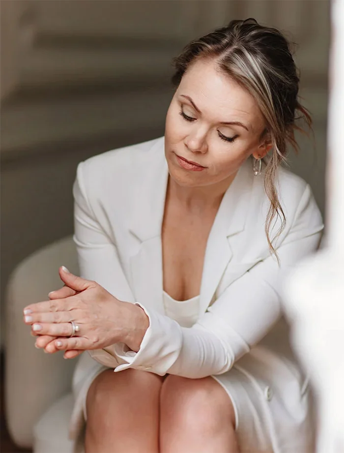 Woman in white blazer sitting relaxed with eyes closed in elegant minimalist interior setting - Hand rejuvenation in Chevy Chase, MD