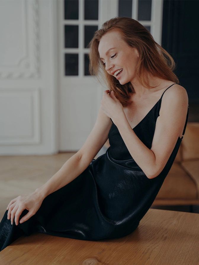 Woman in elegant black dress sitting on floor in minimalist white interior room - Arm lift in Chevy Chase, MD