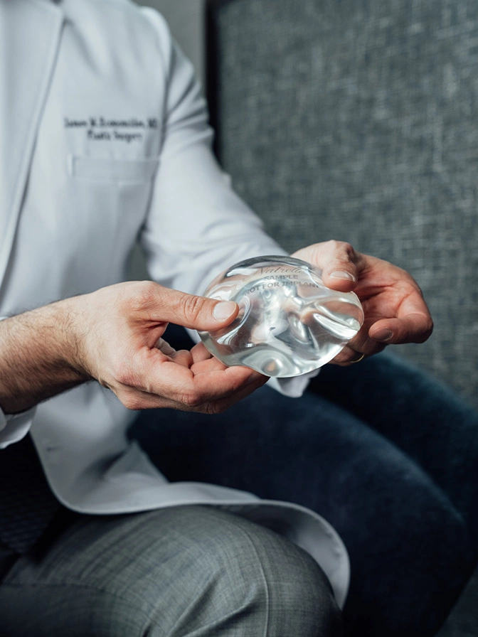 Professional holding transparent diamond model demonstrating gemstone quality and clarity assessment - Breast implant removal in Chevy Chase, MD