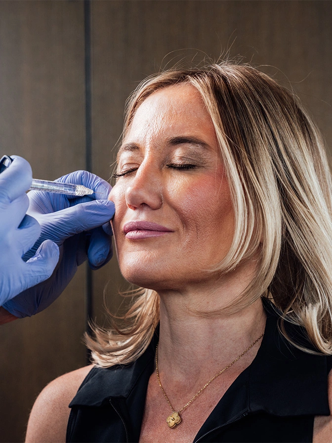 Woman receiving cosmetic injection treatment in her face from medical professional wearing blue gloves - Sculptra in Chevy Chase, MD